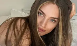 Kobieta z brązowymi włosami i pasemkami blond na przodzie, leżąca na łóżku.