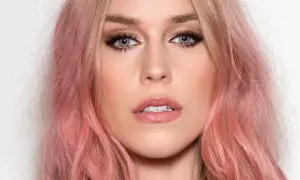 Kobieta z włosami w odcieniu strawberry blonde, z niebieskimi oczami i delikatnym makijażem.