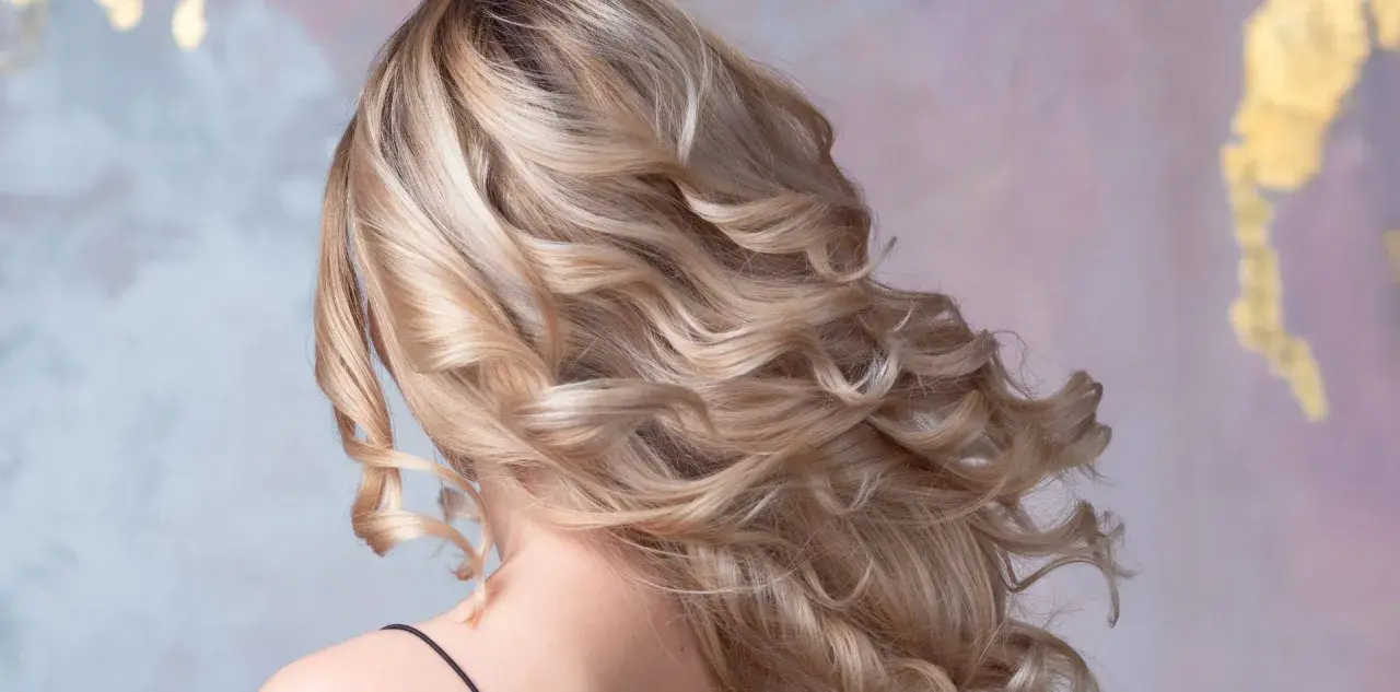 Piękne, falowane blond włosy z subtelnym cieniowaniem, które dodaje im objętości i blasku.